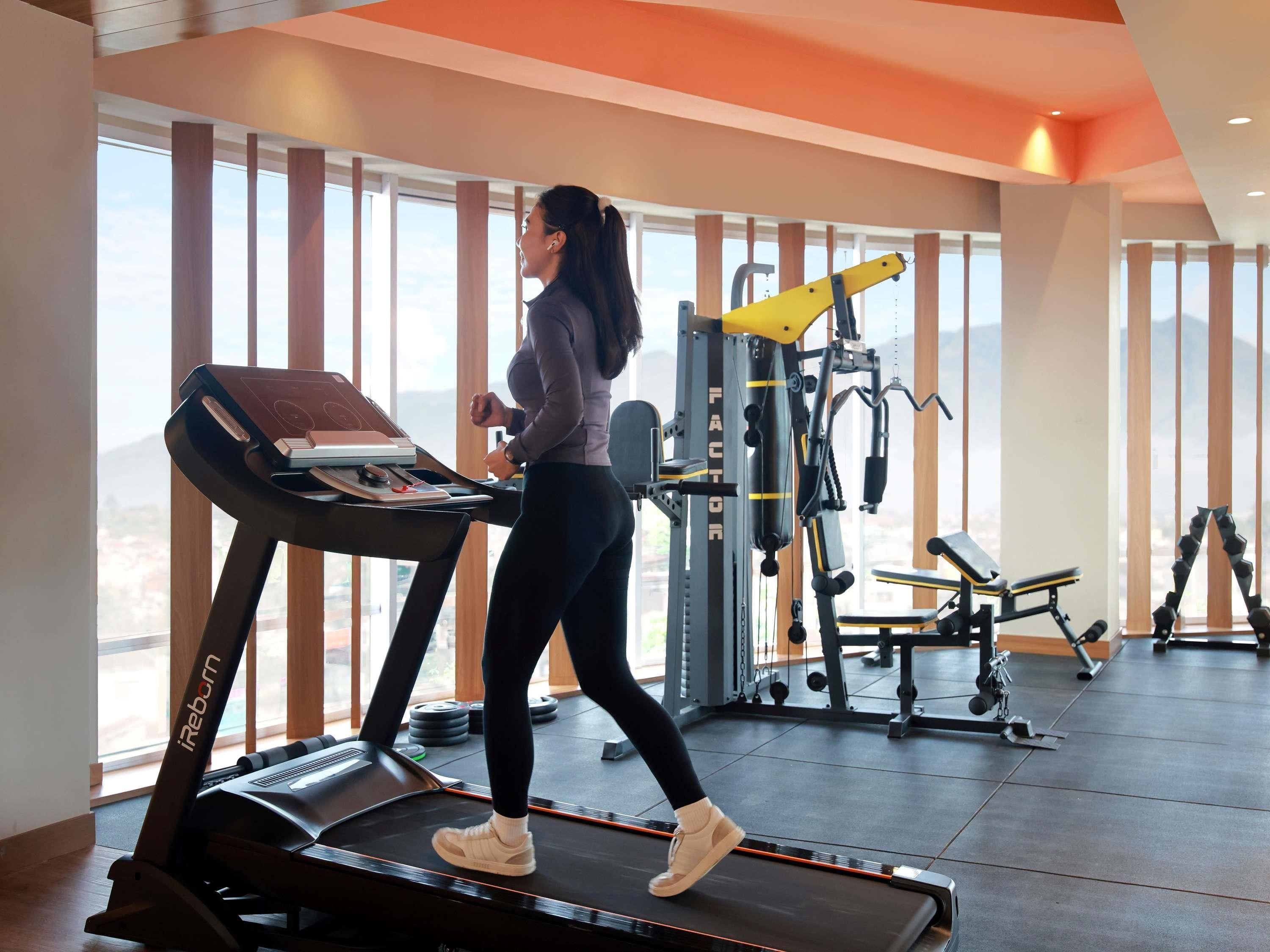 A gym with a treadmill, weight machines, and a large window with a view.
