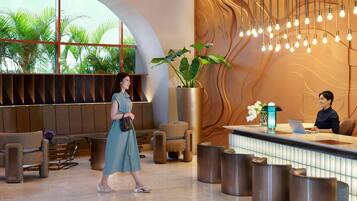 A modern lobby with a reception desk, seating area, and large windows overlooking greenery.