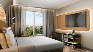 A modern hotel room with a large bed, a desk, a TV, and a view of the outdoors. - Mercure Garut City Center (Garut)