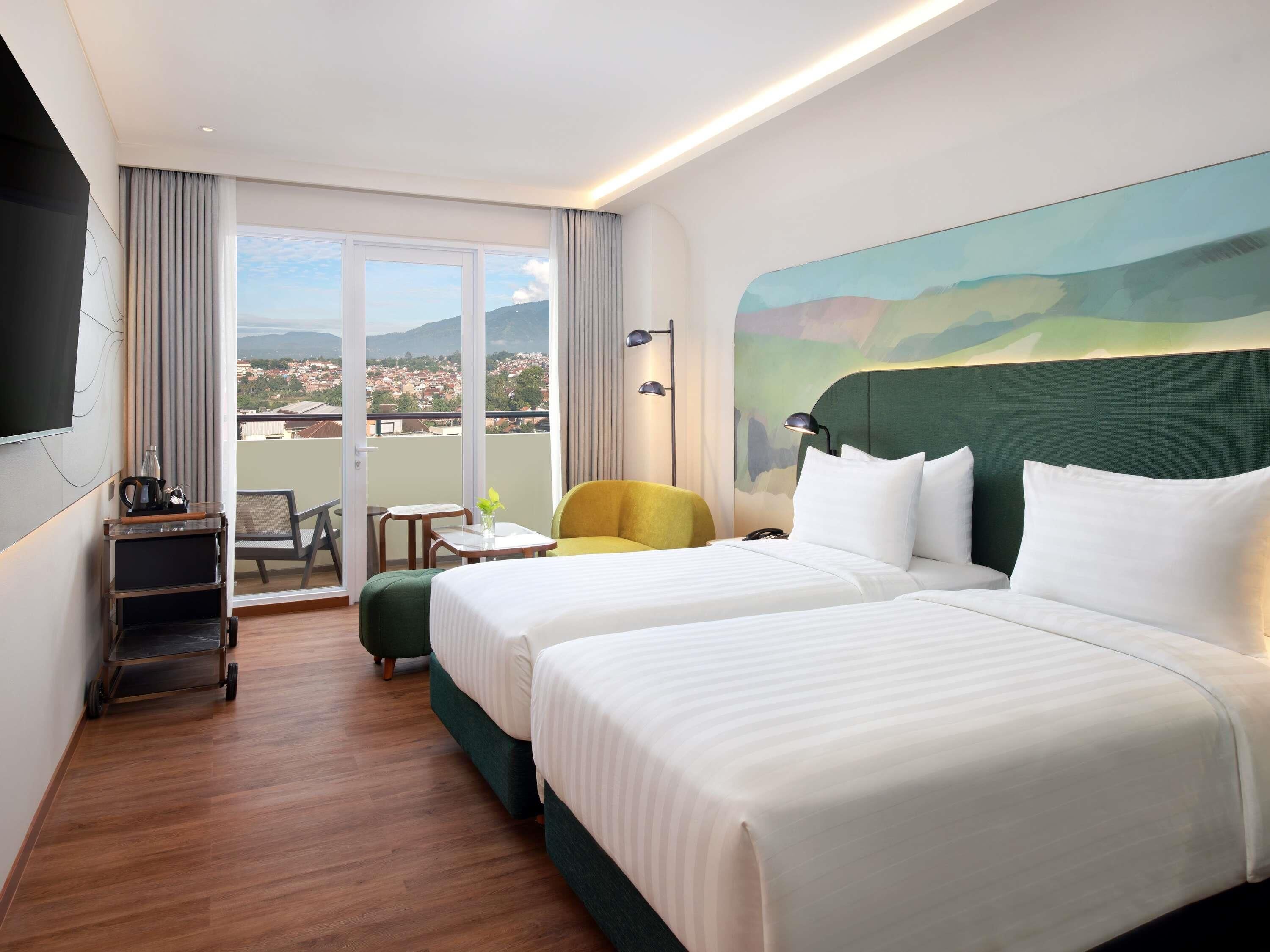 A hotel room with two beds, a balcony with a view, a small table, and a chair.
