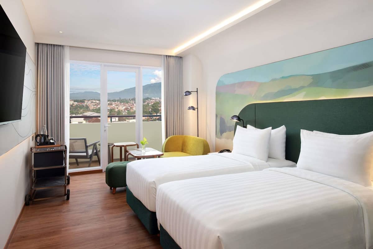 A hotel room with two beds, a balcony with a view, a small table, and a chair.