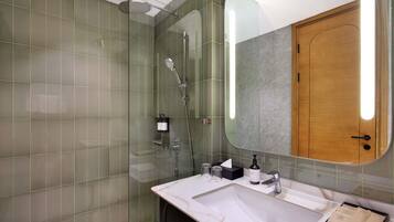 A modern bathroom with a glass-enclosed shower, a marble sink, and a wooden door.