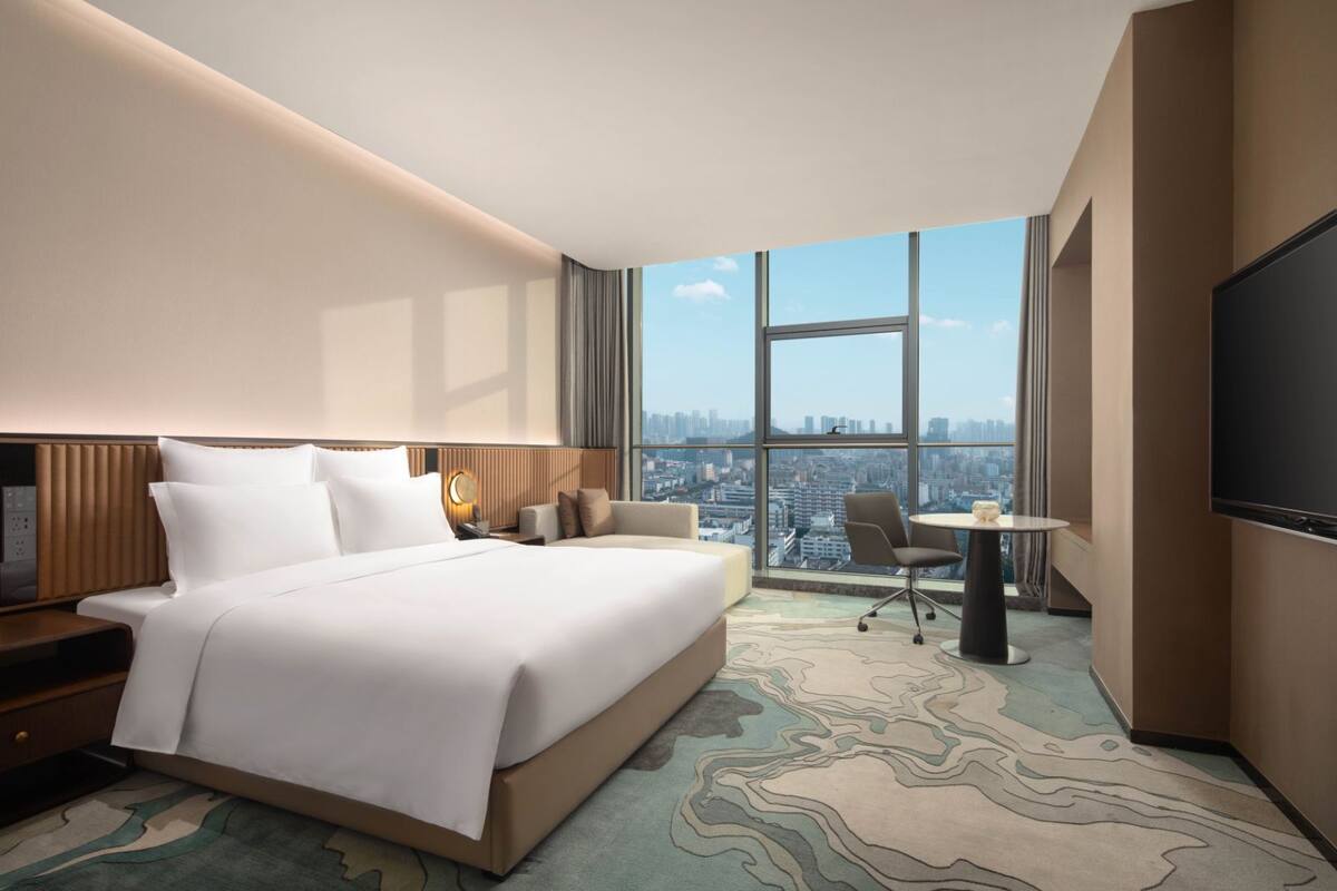 Ein modernes Hotelzimmer mit einem großen Bett, einem Schreibtisch und einem Fernseher.