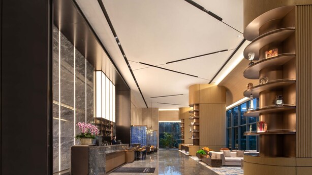 A modern lobby with a reception desk, seating area, and a large bookshelf. - Novotel Lianyungang Haizhou (Lianyungang)