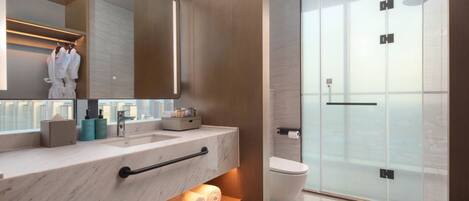 Une salle de bain moderne avec un comptoir en marbre, un grand miroir, une douche en verre et des toilettes.