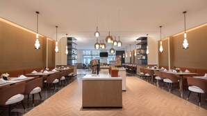 A spacious restaurant with a central island, multiple dining tables, and hanging pendant lights. - Novotel Lianyungang Haizhou (Lianyungang)