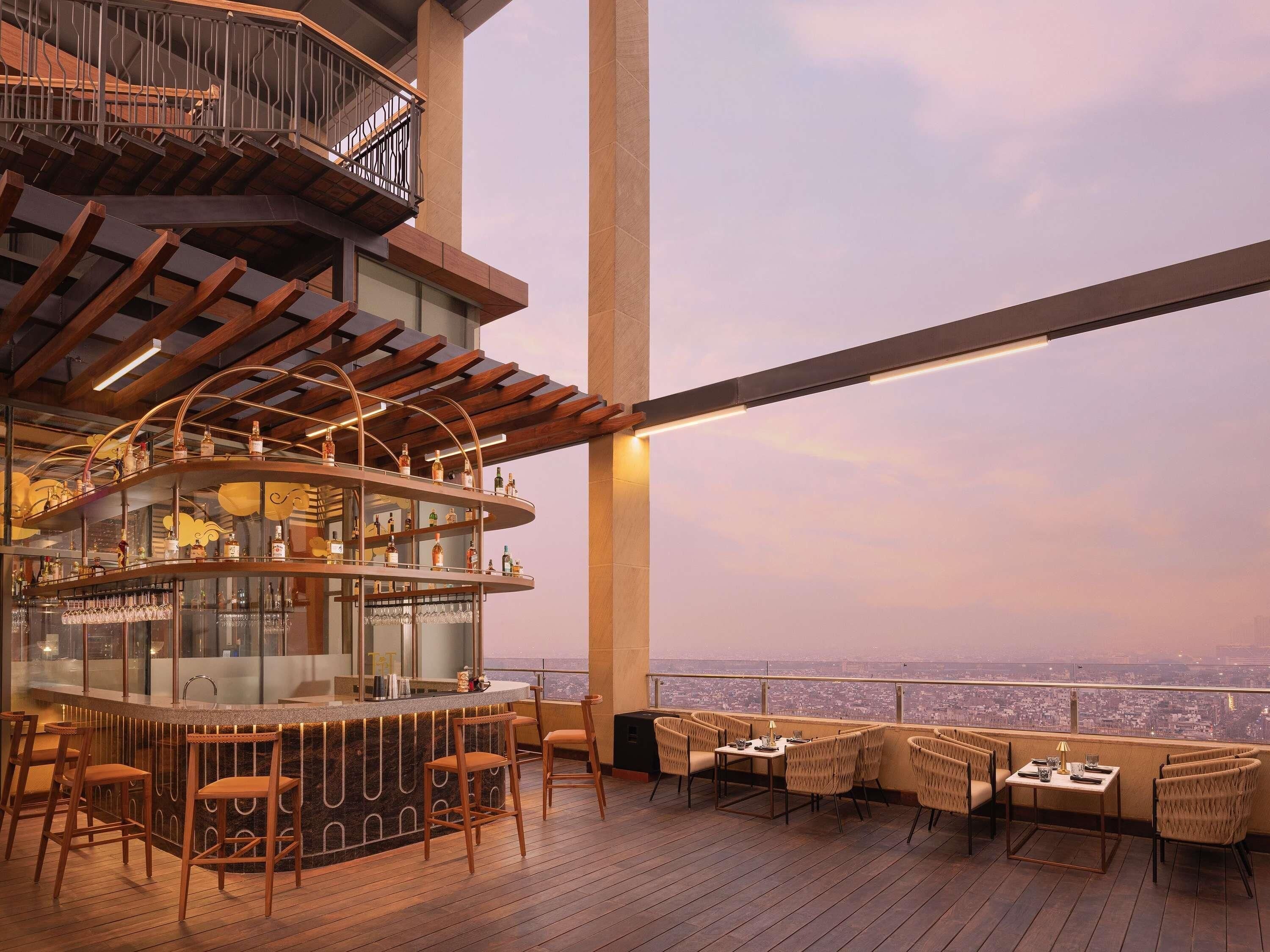 A bar area with a curved counter, multiple seating options, and a city view.