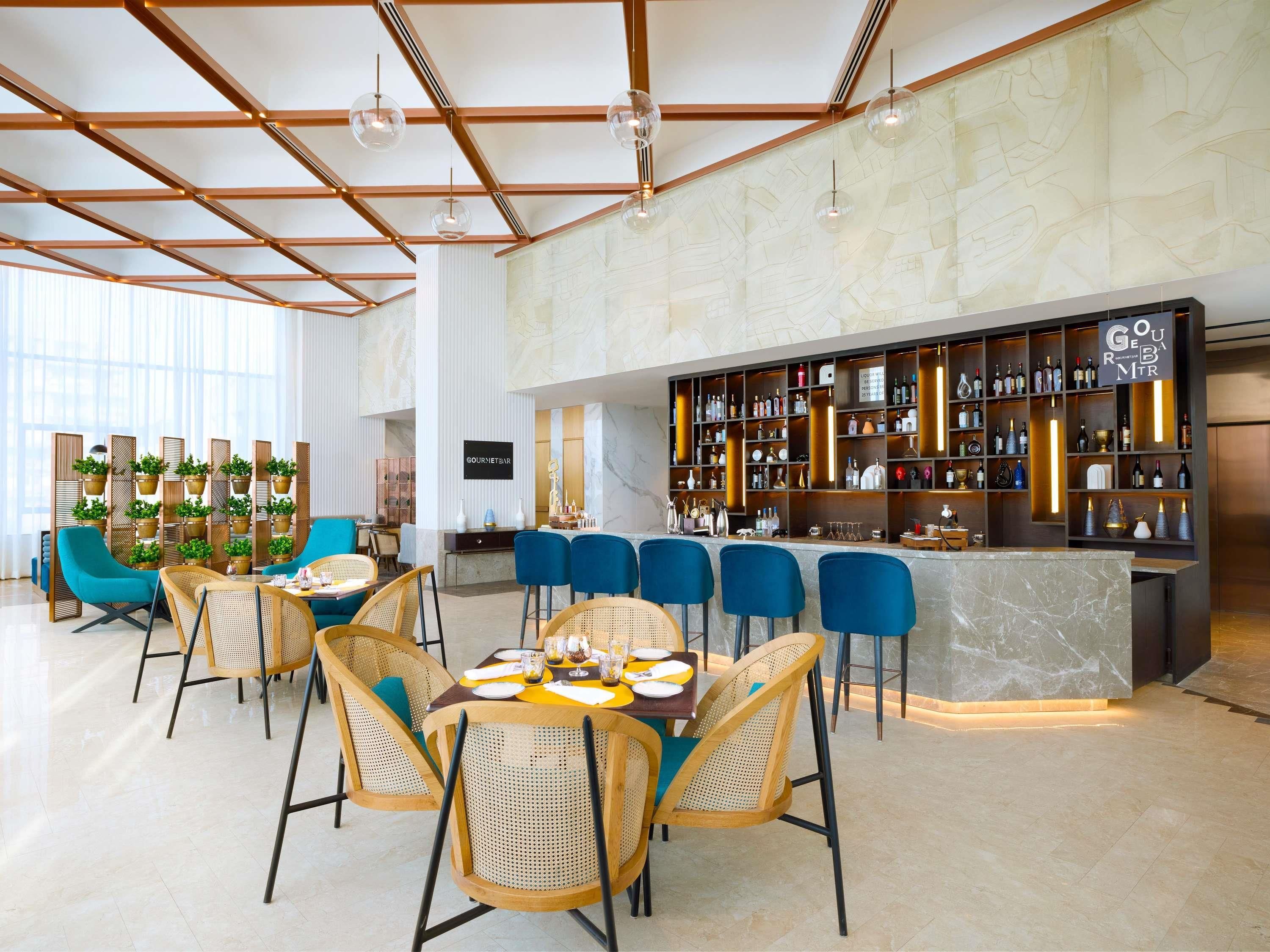 A modern bar area with a marble countertop, bar stools, and a variety of bottles and glasses.