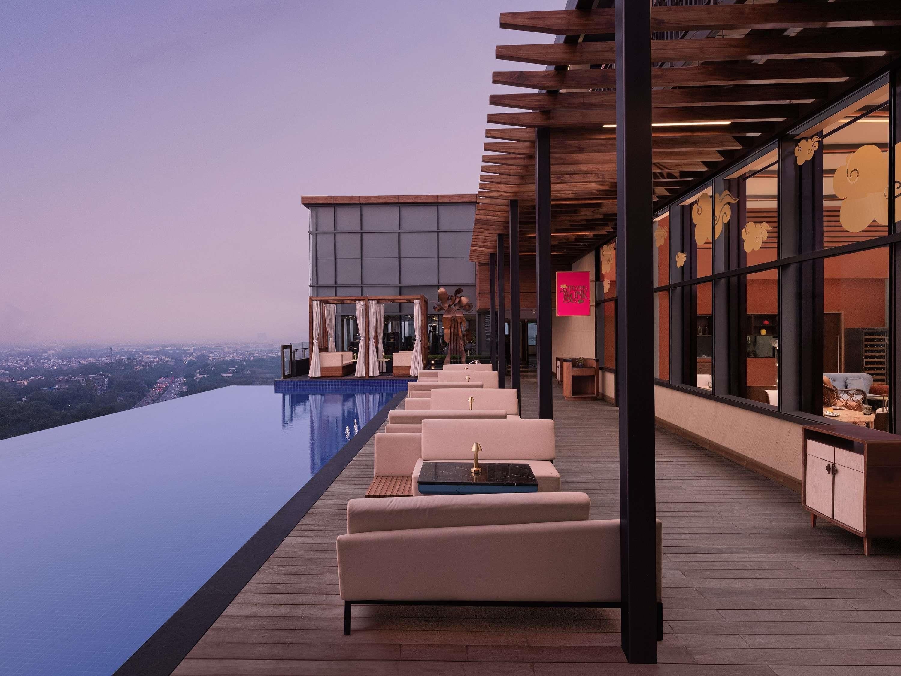 An infinity pool with outdoor seating and a view of the city.