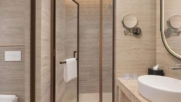 A modern bathroom with a glass shower enclosure, a marble vanity, and a large mirror.