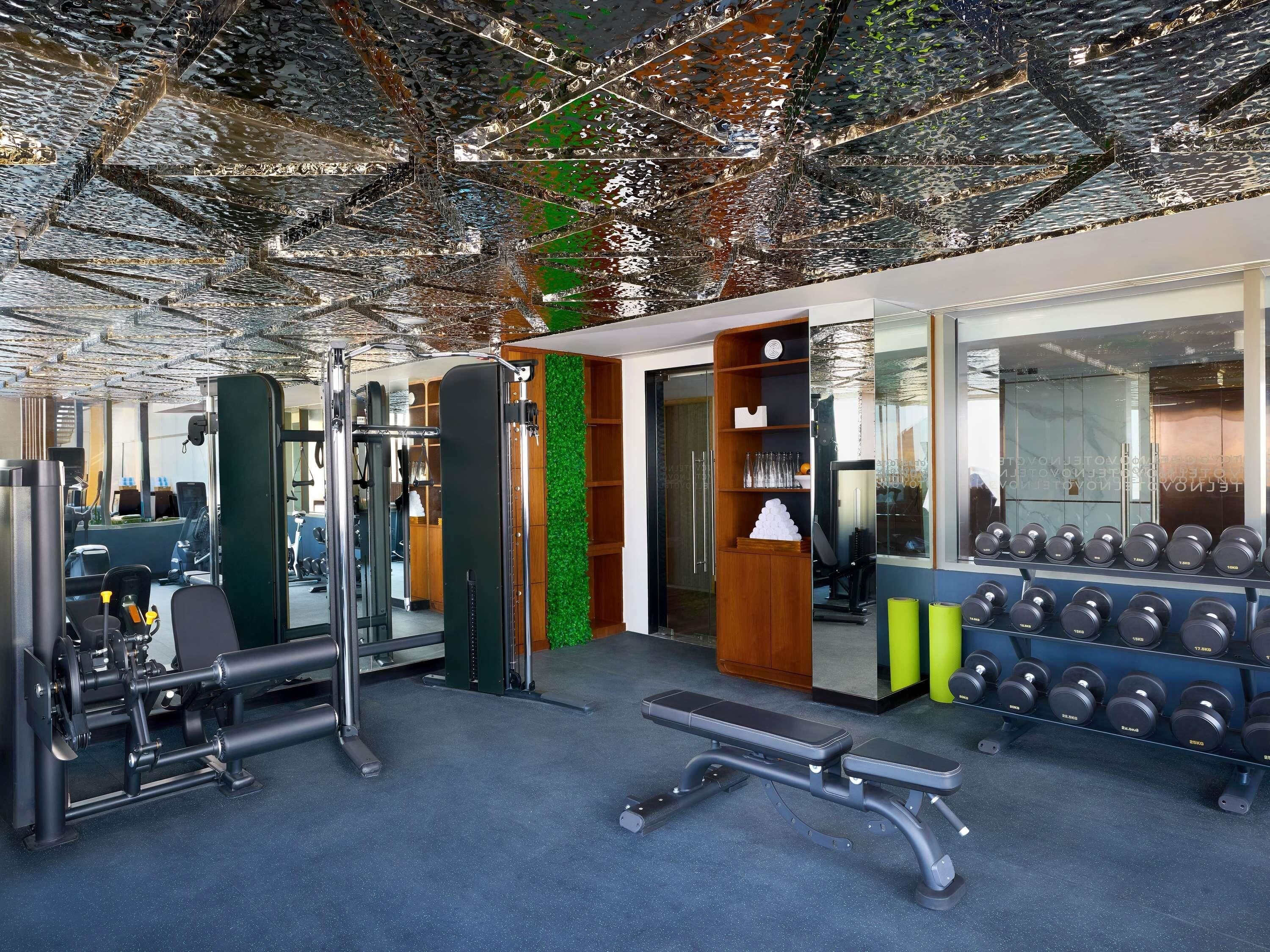 A gym with exercise equipment, a bench, and a wall with mirrors.