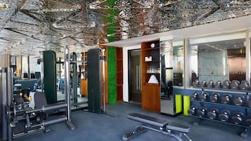 A gym with exercise equipment, a bench, and a wall with mirrors.