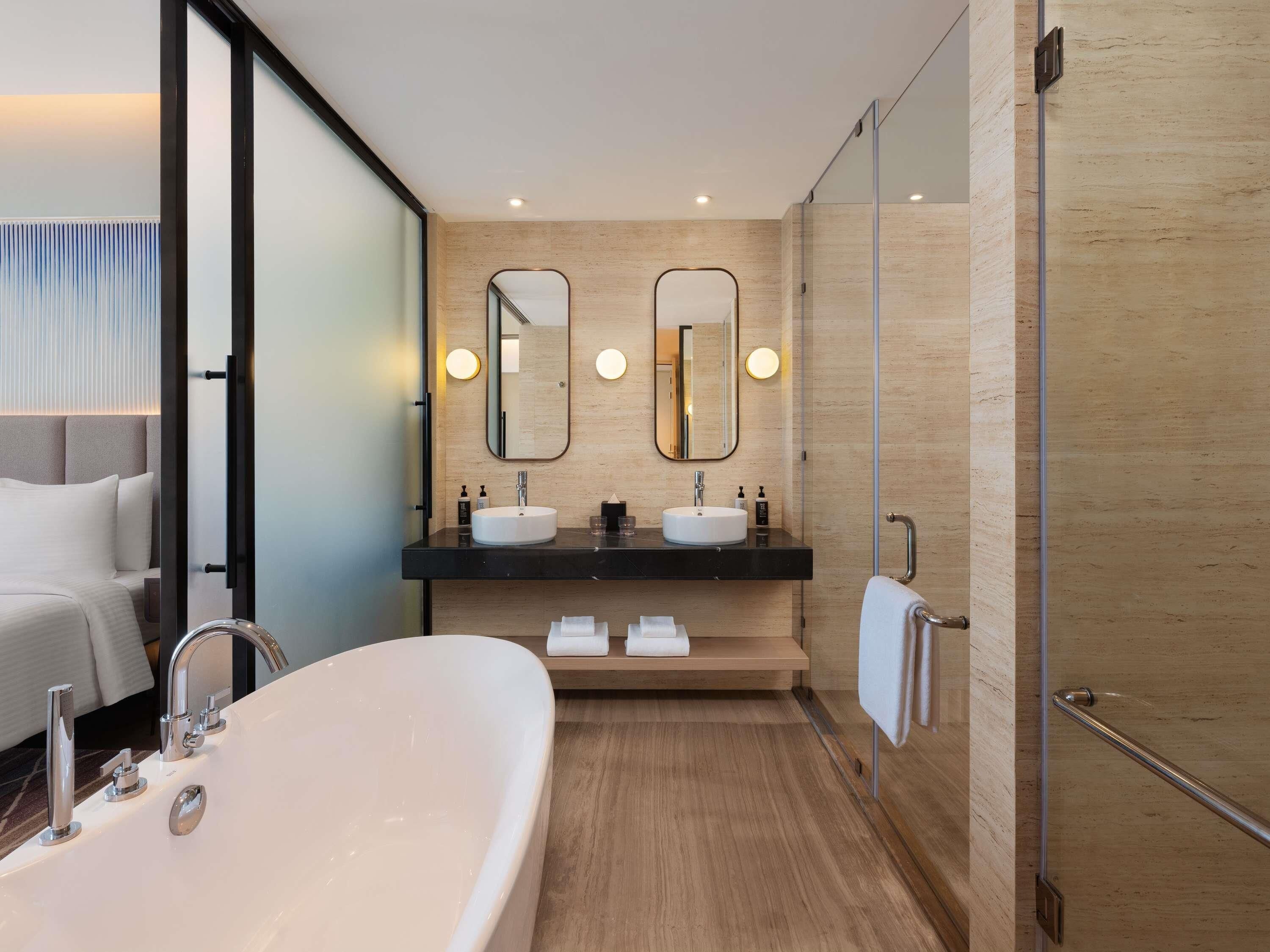 A modern bathroom with a large bathtub, two sinks, and two mirrors.