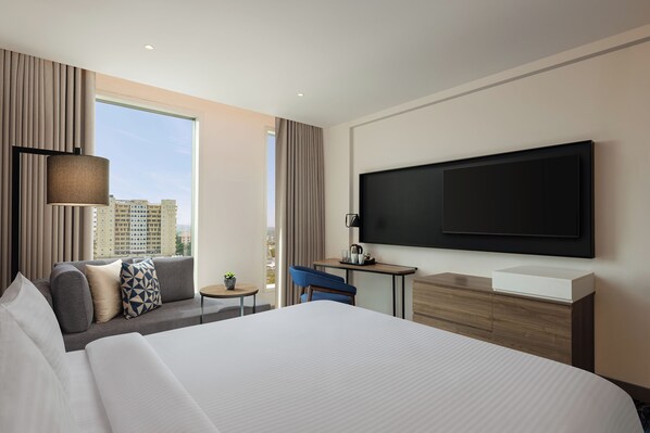 A modern hotel room with a large bed, a desk, a TV, and a city view. - Novotel New Delhi City Centre (New Delhi)