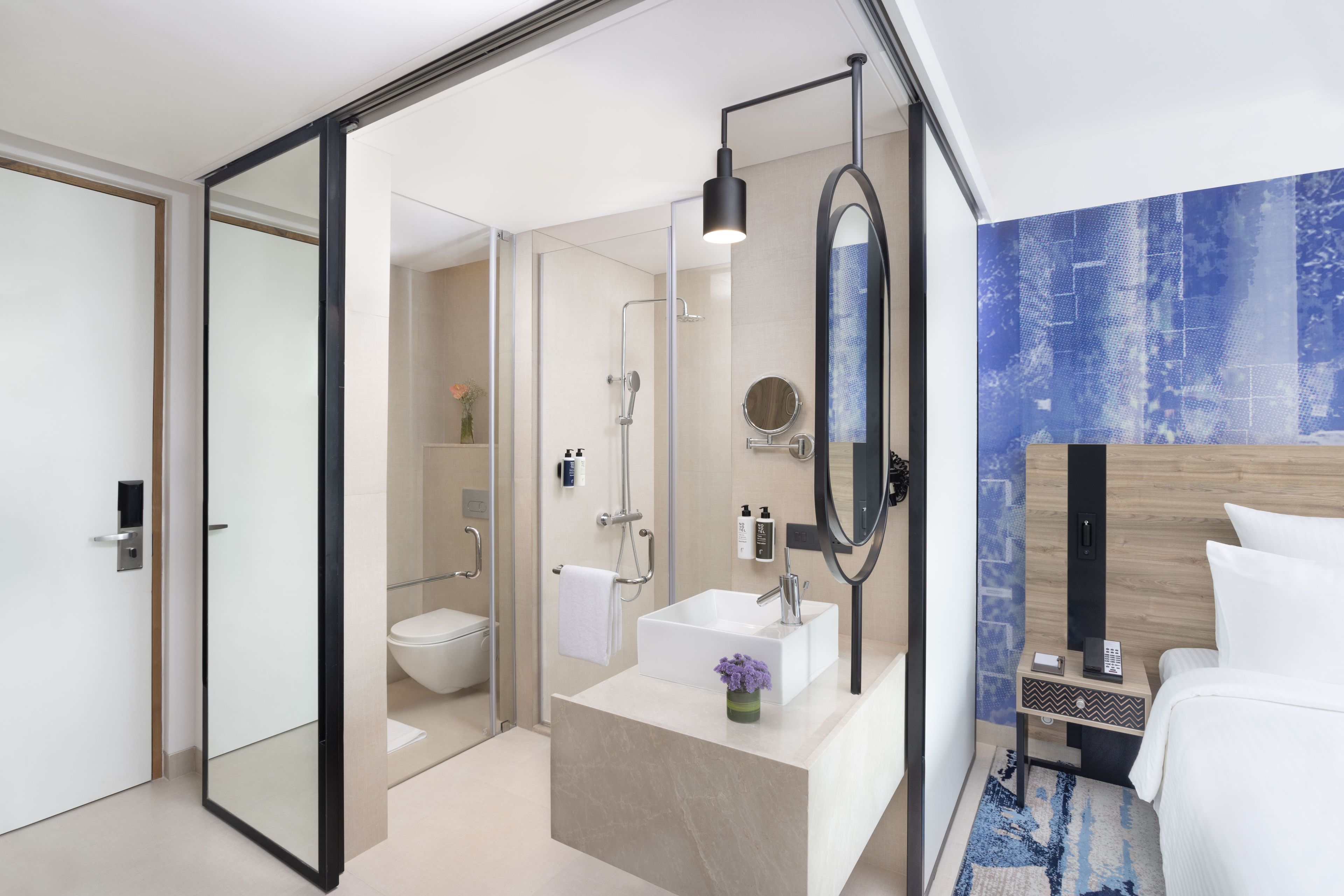 A modern bathroom with a glass shower enclosure, a white sink, and a large mirror.