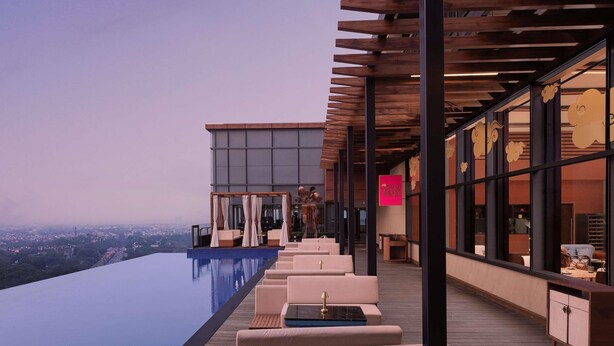 Una piscina infinita con asientos exteriores y vistas de la ciudad.