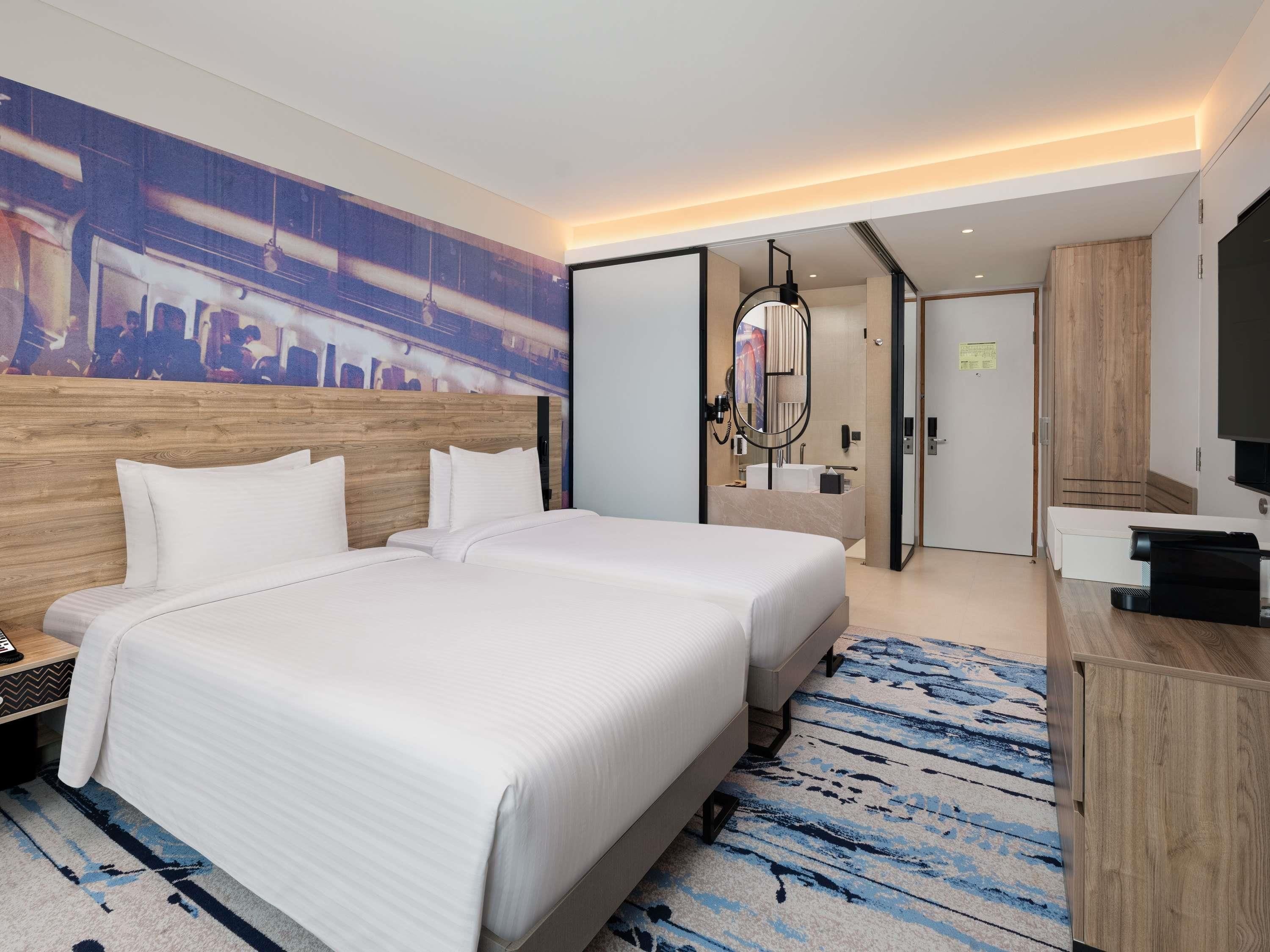 A hotel room with a large bed, a desk, a mirror, and a television.