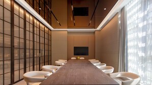 A conference room with a long table and modern chairs, large windows, and a flat-screen TV. - Pullman Renhuai Chuangmeng (Zunyi)