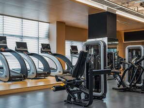 Un gimnasio con cintas de correr, máquinas de pesas y equipo de ejercicio.