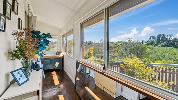 A narrow room with a bench, a large window, and a view of a forested area.