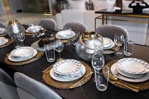 A dining table set with plates, glasses, and cutlery, arranged on woven placemats.