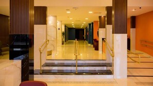 A hotel lobby with marble flooring, a staircase with golden railings, and a modern design. - Ibis Styles Foz Do Iguaçu (Foz do Iguaçu)