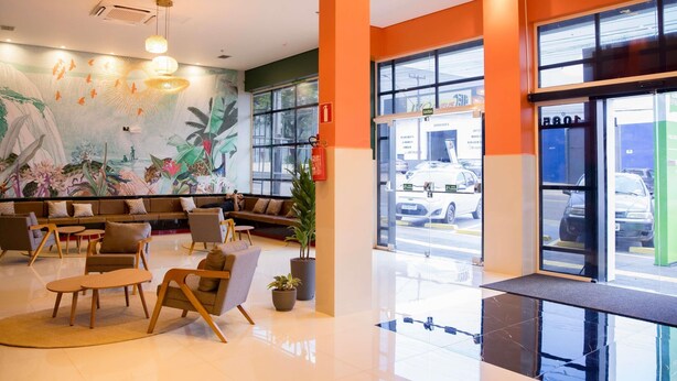 A modern lobby with a seating area, large windows, and a mural on the wall. - Ibis Styles Foz Do Iguaçu (Foz do Iguaçu)