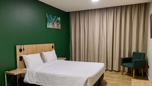A hotel room with a bed, bedside tables, a chair, a painting on the wall, and a curtain. - Ibis Styles Foz Do Iguaçu (Foz do Iguaçu)