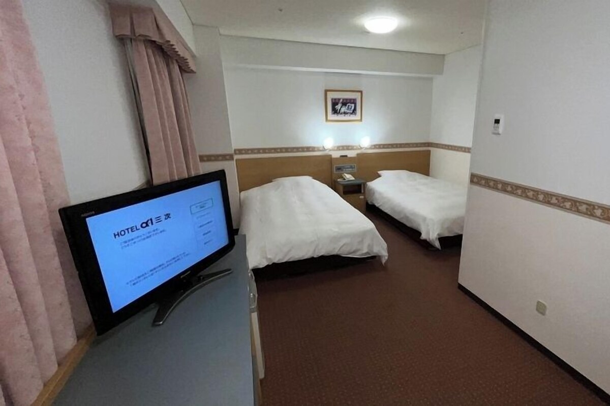 A hotel room with two beds, a desk with a computer, and a framed picture on the wall.