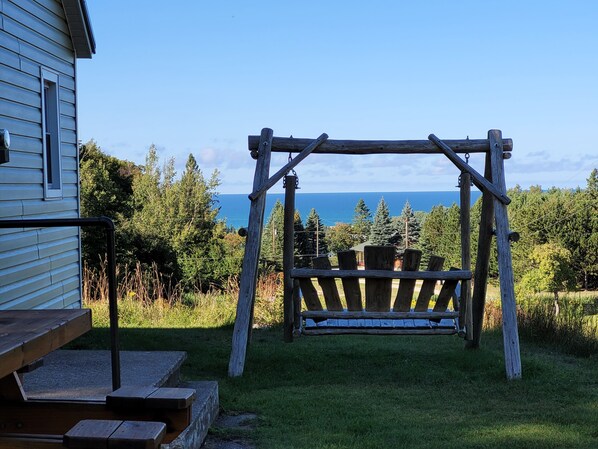 Une balançoire en bois installée dans un espace verdoyant, avec vue sur l’océan.