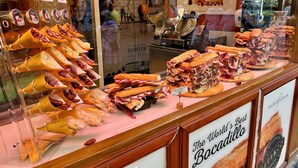 Mostrador de charcutería con diversos embutidos y sándwiches expuestos en una vitrina.