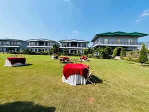 Un hotel con varias edificaciones, zonas de estar al aire libre con mesas redondas y un césped cuidado.