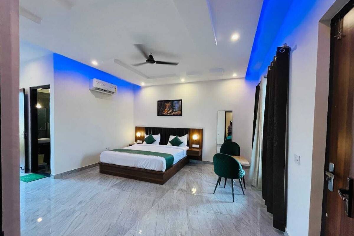 A modern bedroom with a bed, a desk, a chair, a ceiling fan, and an air conditioning unit.