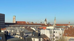 Un paisaje urbano con una mezcla de edificios históricos y modernos, incluyendo una torre destacada con una cúpula y un campanario.