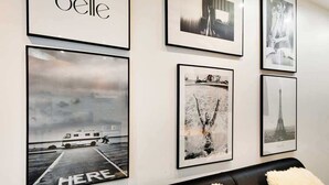A wall with various framed photographs, including a boat on a dock and the Eiffel Tower. - Super appartment-2BR/6p-Bastille (Paris)
