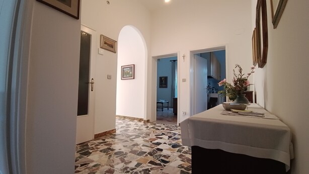 A hallway with a tiled floor, a door, and a table with a vase of flowers.