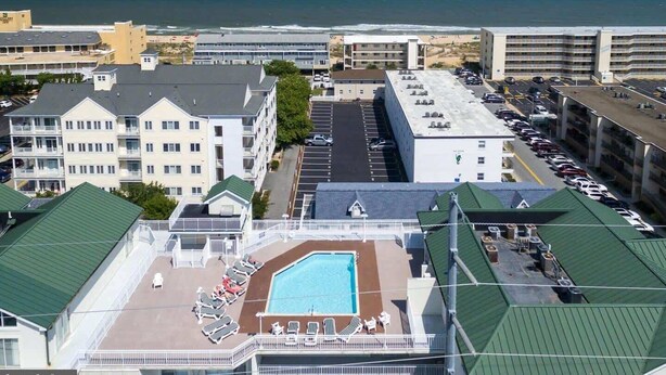 A hotel with a rooftop pool, parking lot, and ocean view.