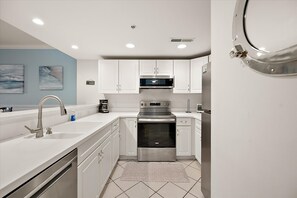 A modern kitchen with white cabinets, stainless steel appliances, and a tiled backsplash.