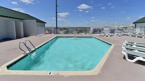 A rectangular swimming pool with a no diving sign, surrounded by lounge chairs and a clear sky.