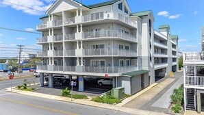 A multi-story hotel with balconies, a parking area, and a clear sky.