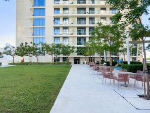 A modern building with multiple floors, outdoor seating area, and a well-maintained lawn.