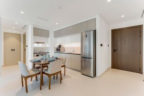 A modern kitchen with a stainless steel refrigerator, a dining table with chairs, and a microwave.