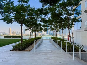 A pathway leading to a building with a view of a city skyline and a body of water.