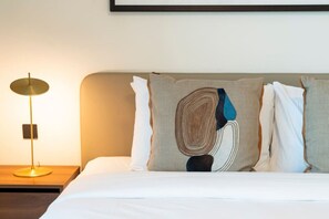 A neatly made bed with a headboard, a bedside lamp, and a framed picture on the wall. - Coastal Chic 1 Bedroom Apartment w private beach (Dubai)