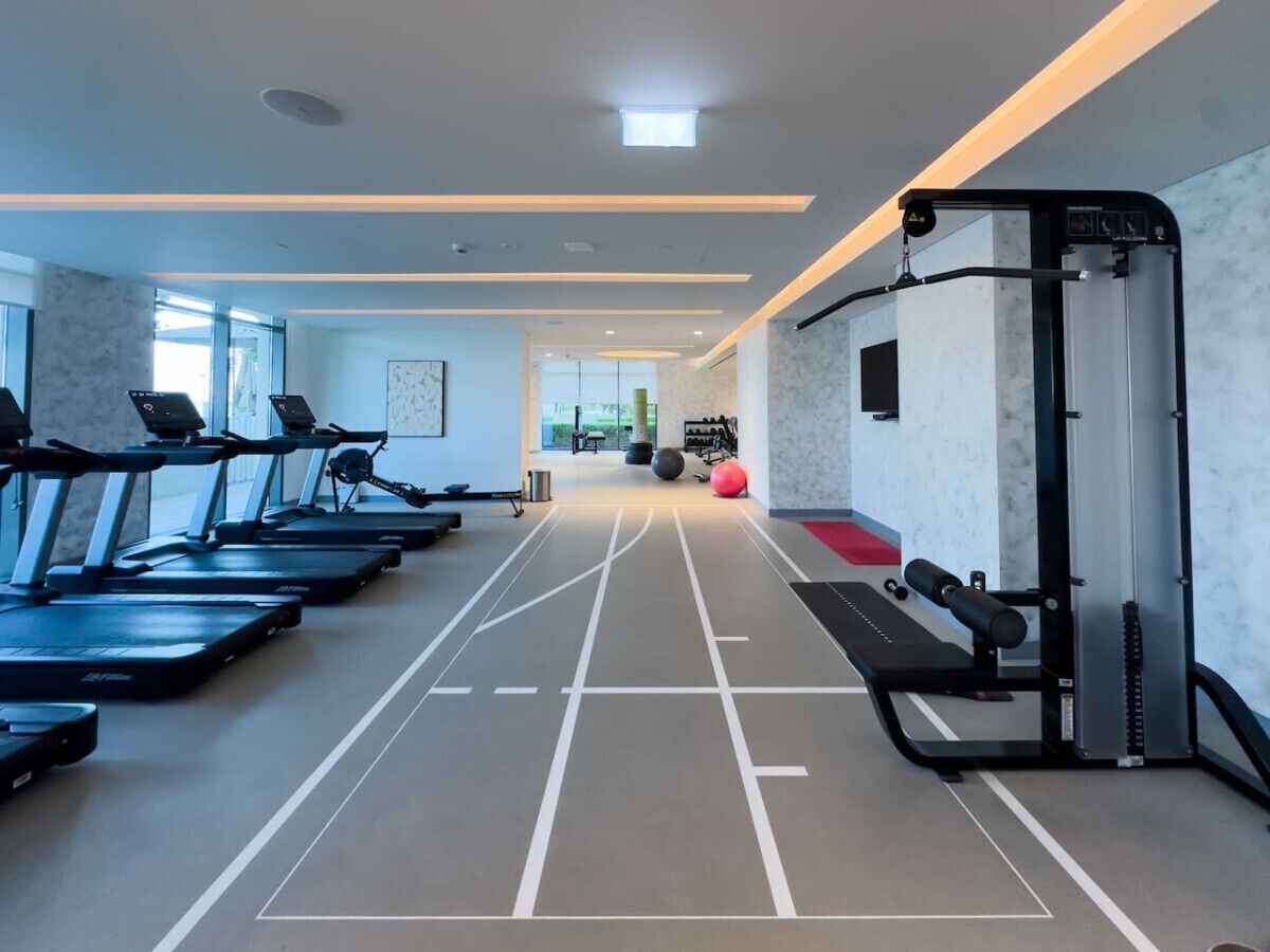 Un gimnasio con cintas de correr, una máquina de remo y un banco para pesas.
