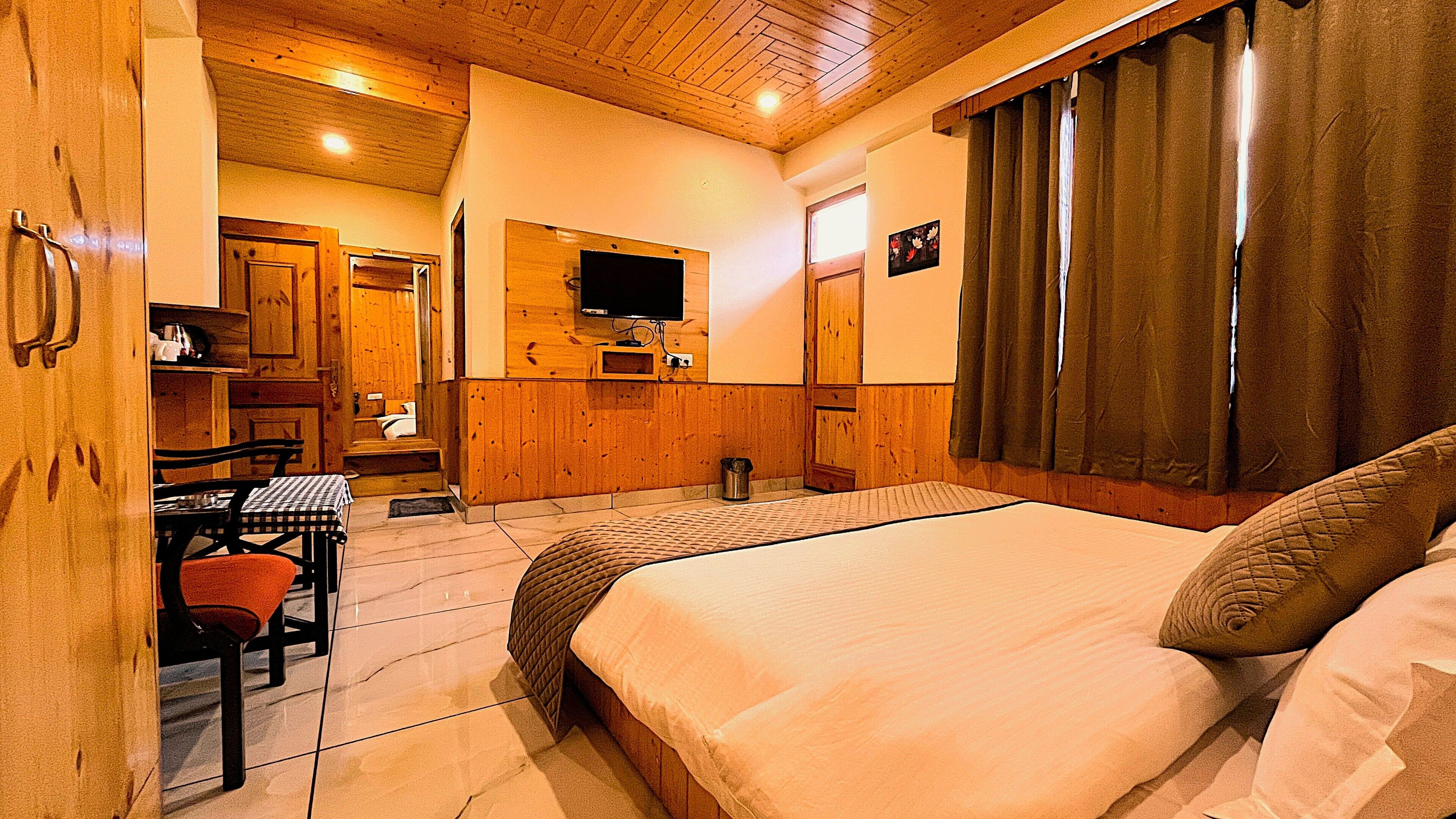 A bedroom with a bed, a desk, and a television.