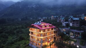 A multi-story hotel with balconies, solar panels, and a view of a mountainous area. - Wander Thrives Inn By Ads (Manali)