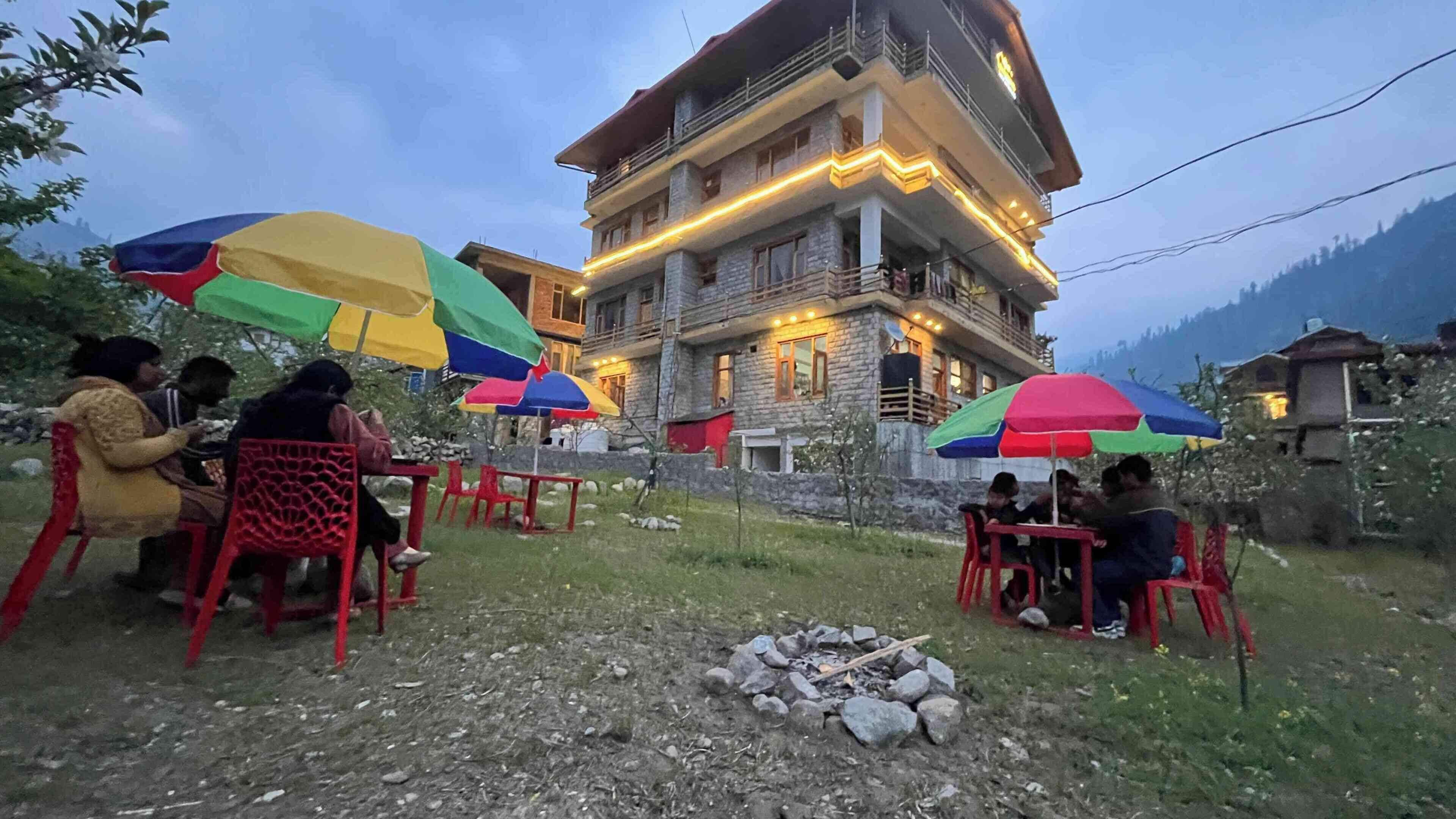 A building with multiple balconies, outdoor seating with colorful umbrellas, and a stone facade.