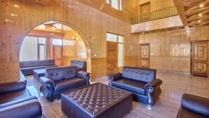 A spacious lobby with wooden paneling, leather sofas, and a central ottoman. - Wander Thrives Inn By Ads (Manali)
