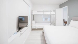 A modern hotel room with a bunk bed, a flat-screen TV, and a desk with a chair.